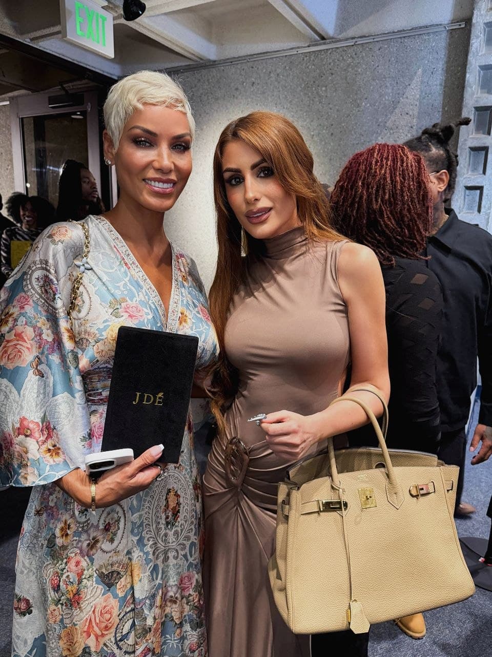 Two guests at an event, one holding a JDÉ presentation package.